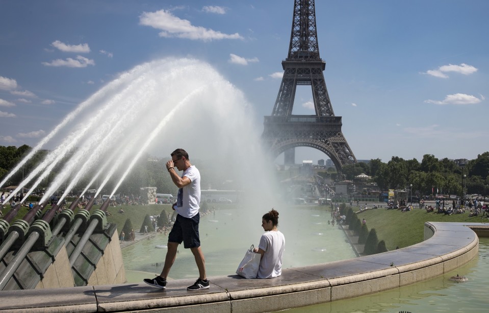 mies kävelee ja nainen istuu Eiffel-tornin edessä.