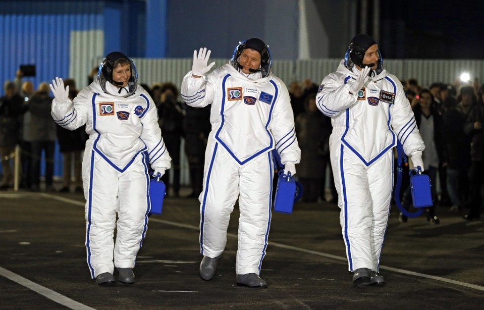 Yksi nais- ja kaksi miesastronauttia heiluttavat