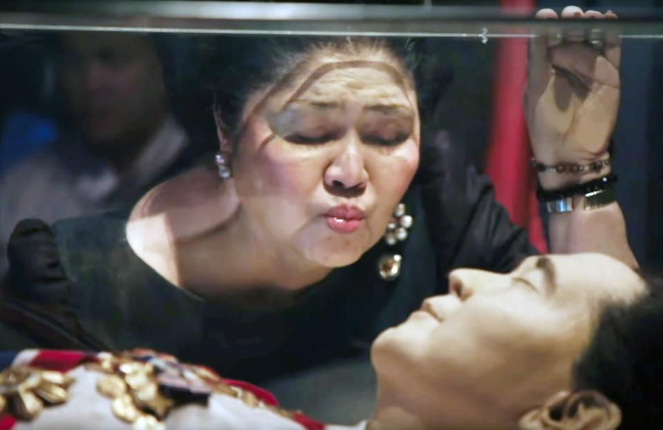 Imelda Marcos suutelee miehensä lasiarkun pintaa. Lasin alla on Ferdinand Marcosin ruumis.