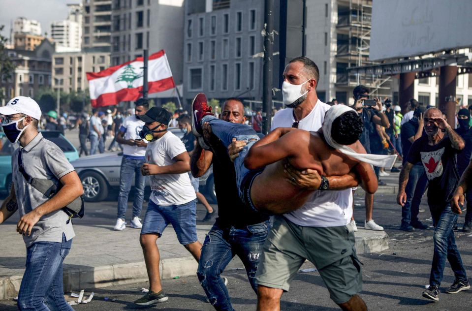Mielenosoittaja kantaa haavoittunutta toveriaan turvaan Beirutin mellakoissa 8.8.2020.