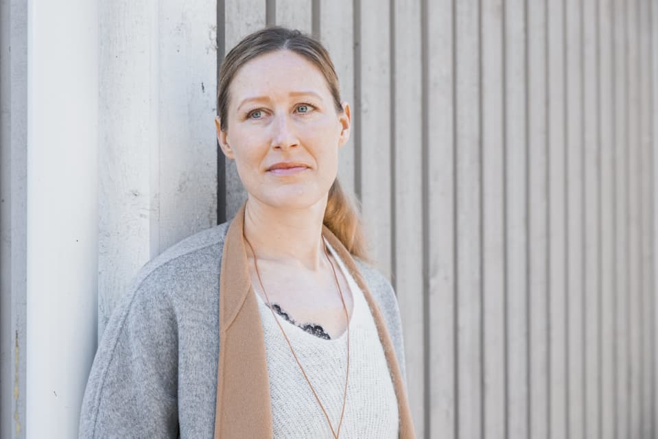 Kiinteistönvälittäjä Johanna Pietilä nojaa seinään kotitalonsa kulmalla.