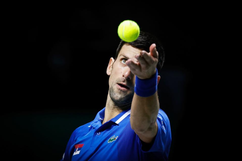 Novak Djokovic kastar upp en tennisboll i luften.