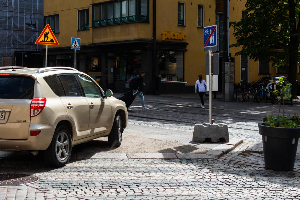 Pienellä Roobertinkadulla Helsingissä on kesäkatu, johon on laitettu istutuksia ja penkkejä. Tie on suljettu toisesta päästä, mutta autoilija ajaa jalkakäytävän kautta.