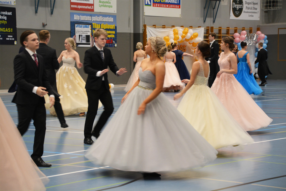 Ungdomar i festkläder dansar omkring i en gympasal.