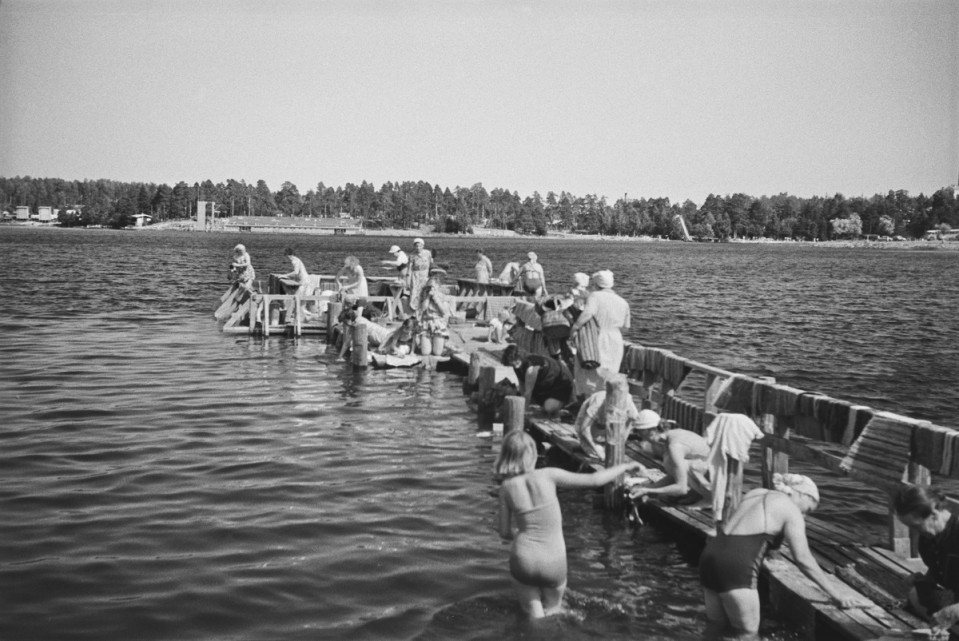 Mustavalkoisessa kuvassa ihmisiä mattolaiturilla