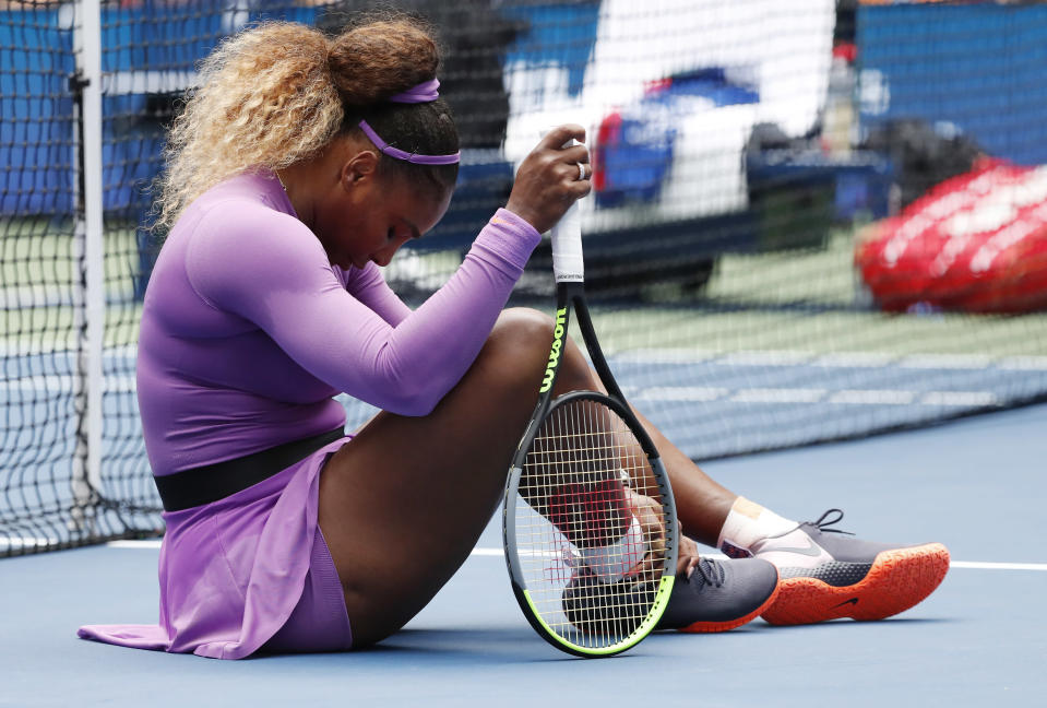Serena Williams sitter på planen och håller om sin vrist.
