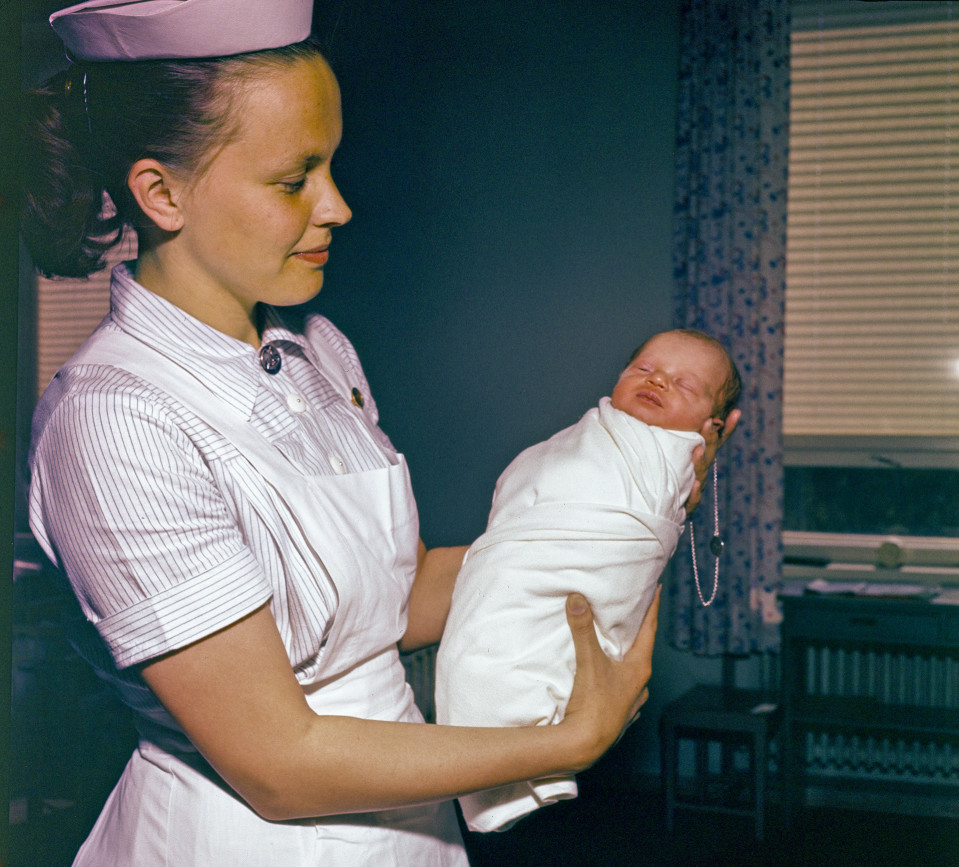 Vastasyntynyt lapsi kapaloituna kätilön käsissä 1960-luvulla.