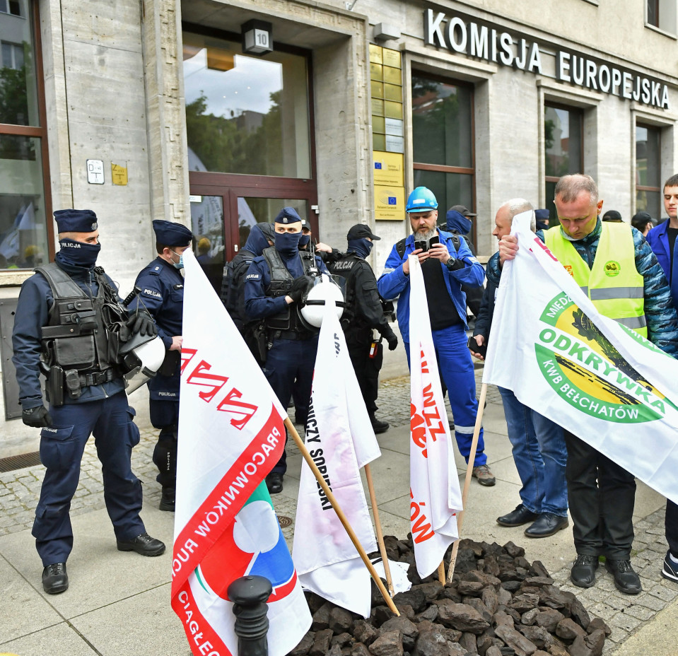 Kaivosmiehiä ja poliiseja kadulla. Takana rakennus, jossa on kyltti