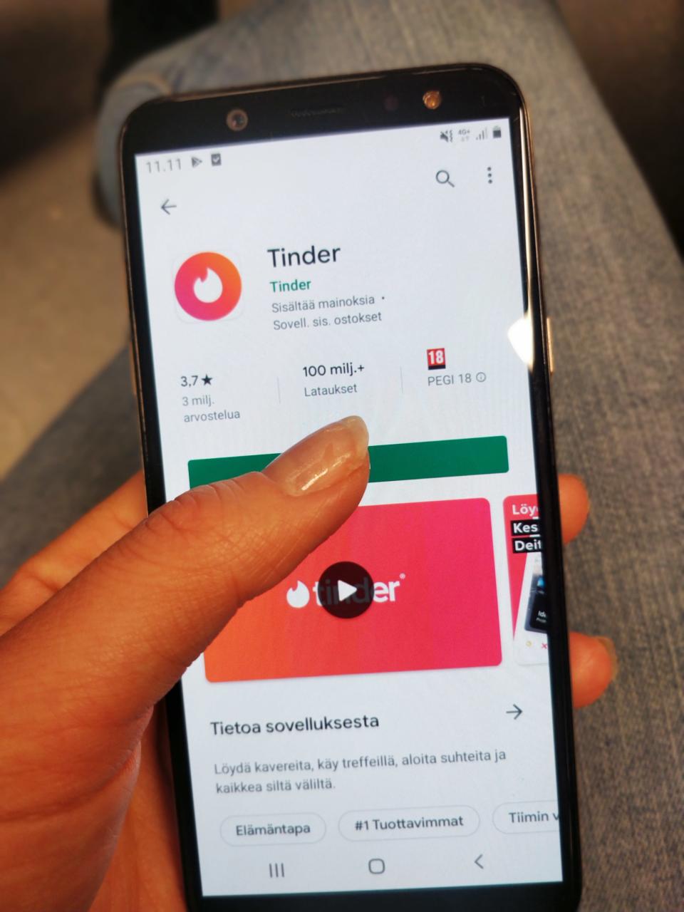 Kuvassa on puhelin, jossa käyttäjä aikoo ladata deittisovelluksen.