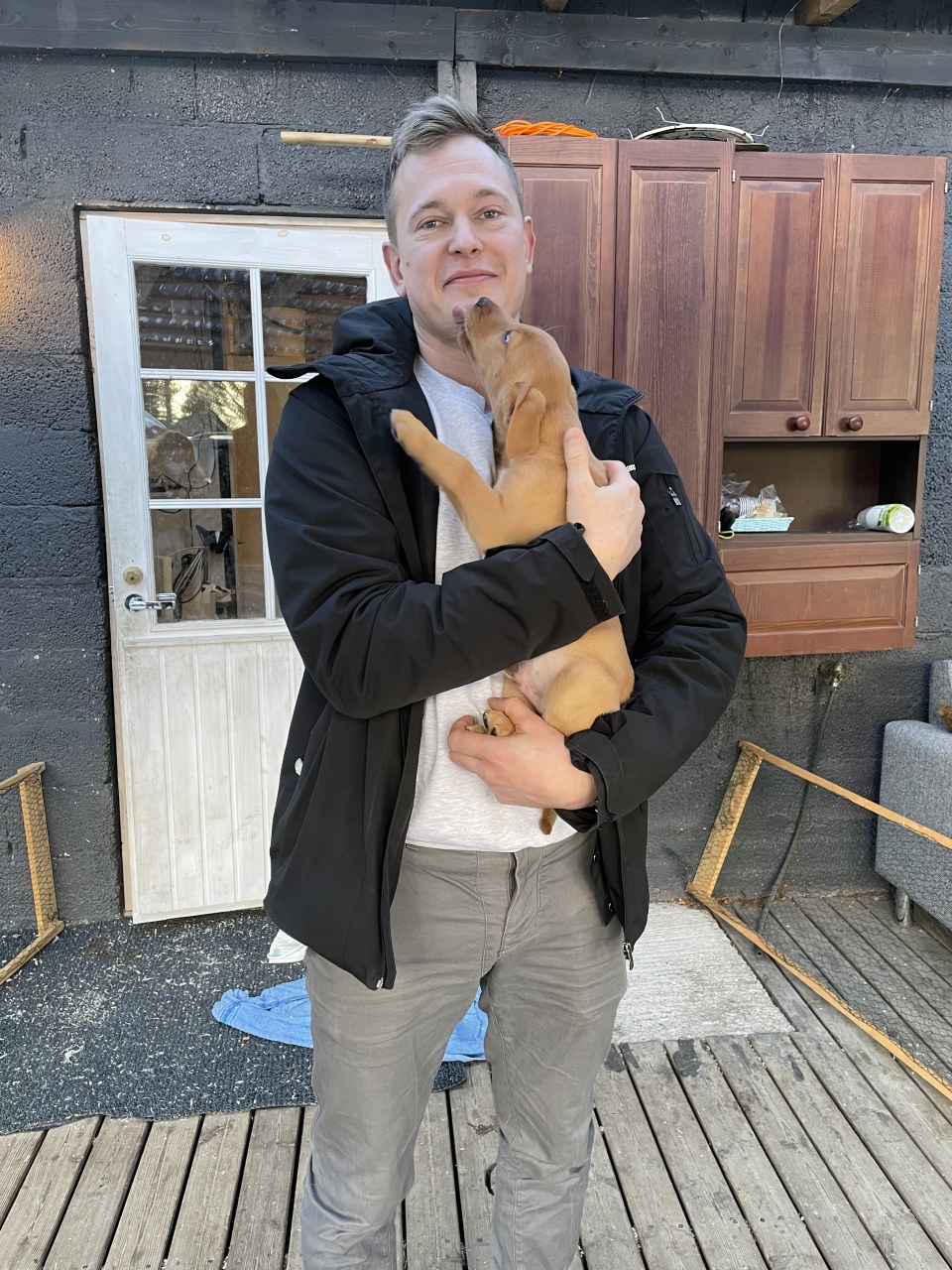 Mies seisoo koiranpentu sylissään.