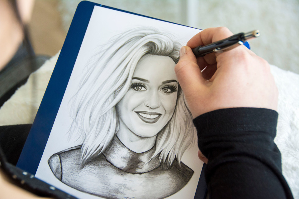 Lähikuva Katja Honkosen kädestä, kun hän piirtää Katy Perryä paperille.