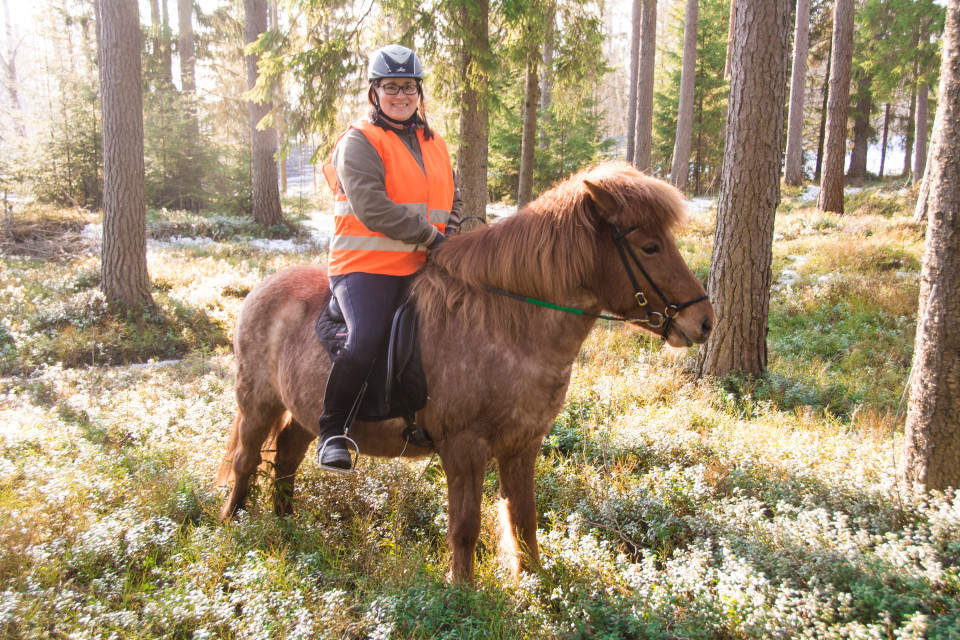 Tiia-Maria Joensuu ratsastaa Mansikka-hevosella metsässä.
