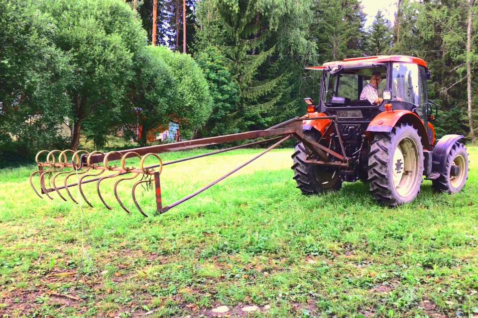Traktoriin on liitetty yli neljä metriä pitä harava, jolla nostetaan leikattu vesikasvillisuus kuivalle maalle.