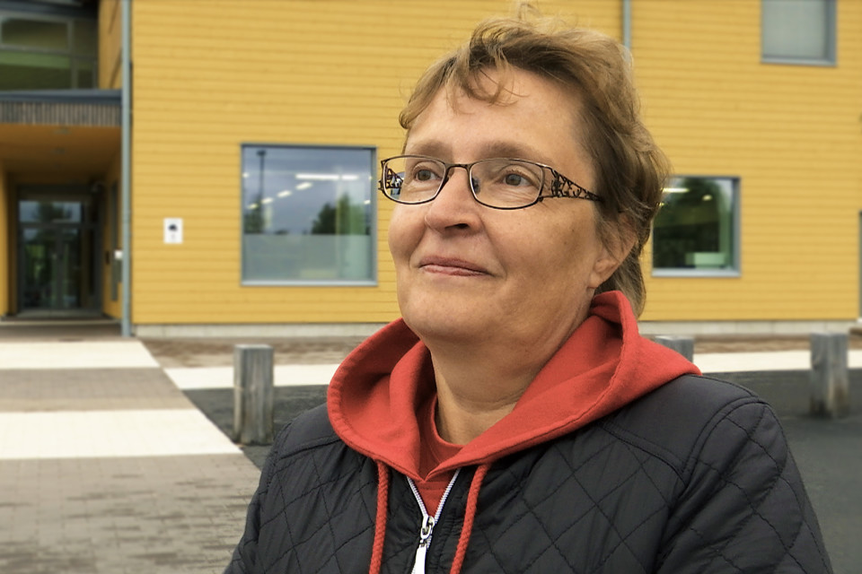 Maija Moilanen seisoo Pudasjärven hirsikoulun edustalla.