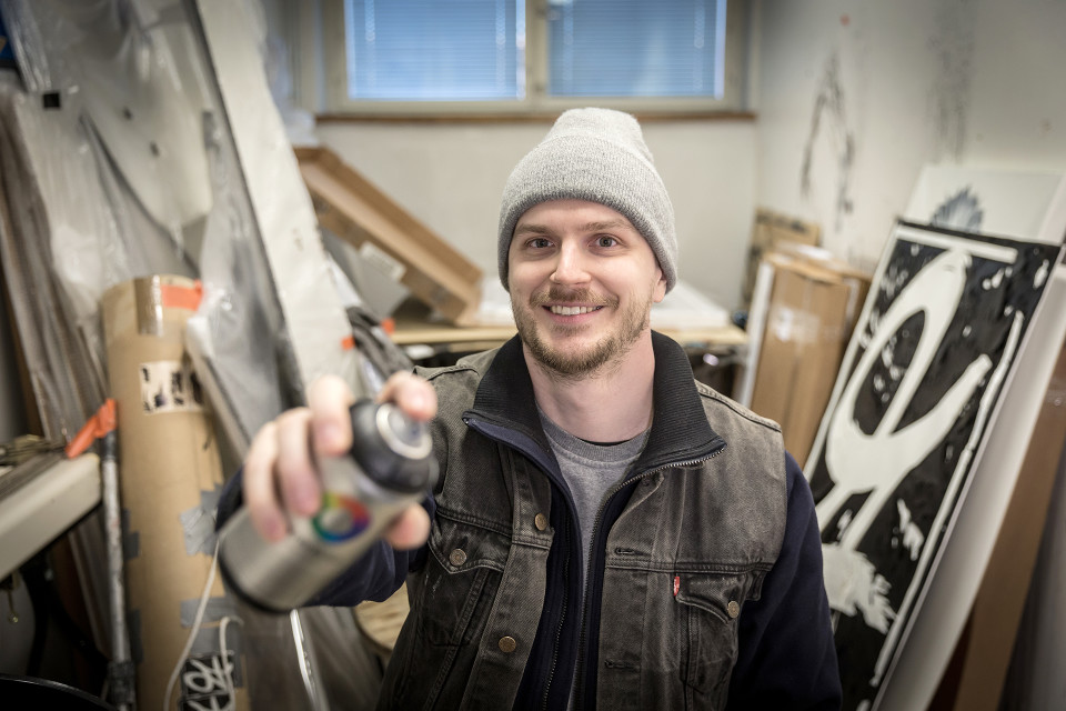 mies ateljeessa spraypullon kanssa