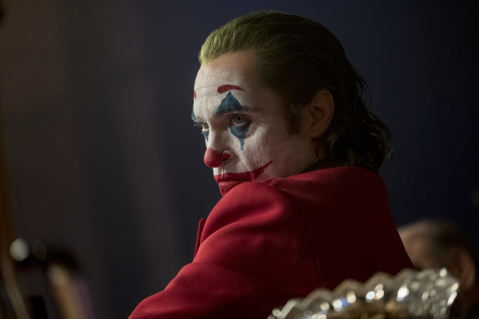 Närbild på Joker (Joaquin Phoenix) iklädd clownmask och röd kostym.