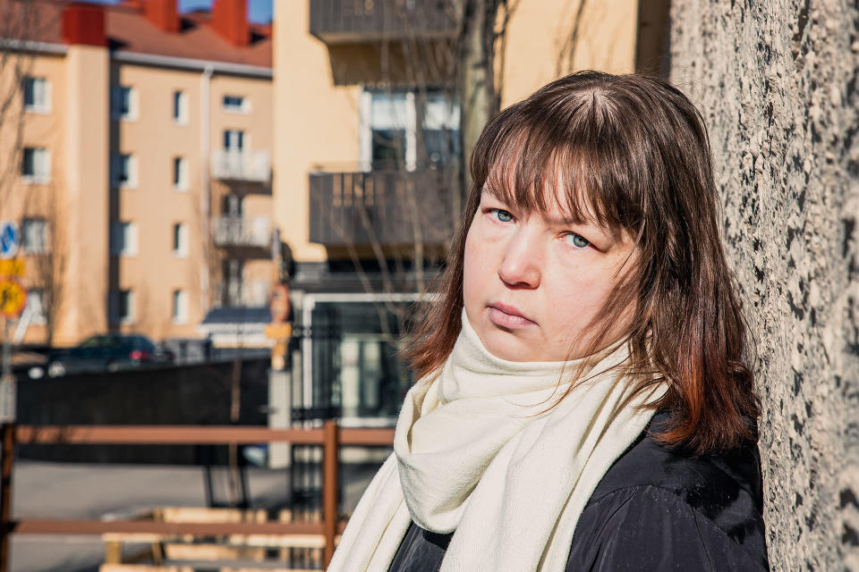 Arja Lehto nojaa seinää vasten ja katsoo kameraan.