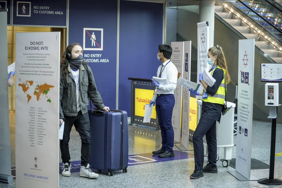 Matkustaja saapuu Helsinki-Vantaan lentoasemalle 7. elokuuta 2020. Häntä vastassa on kaksi henkilöä, joilla on ohjelehtinen Suomeen ulkomailta saapuville.