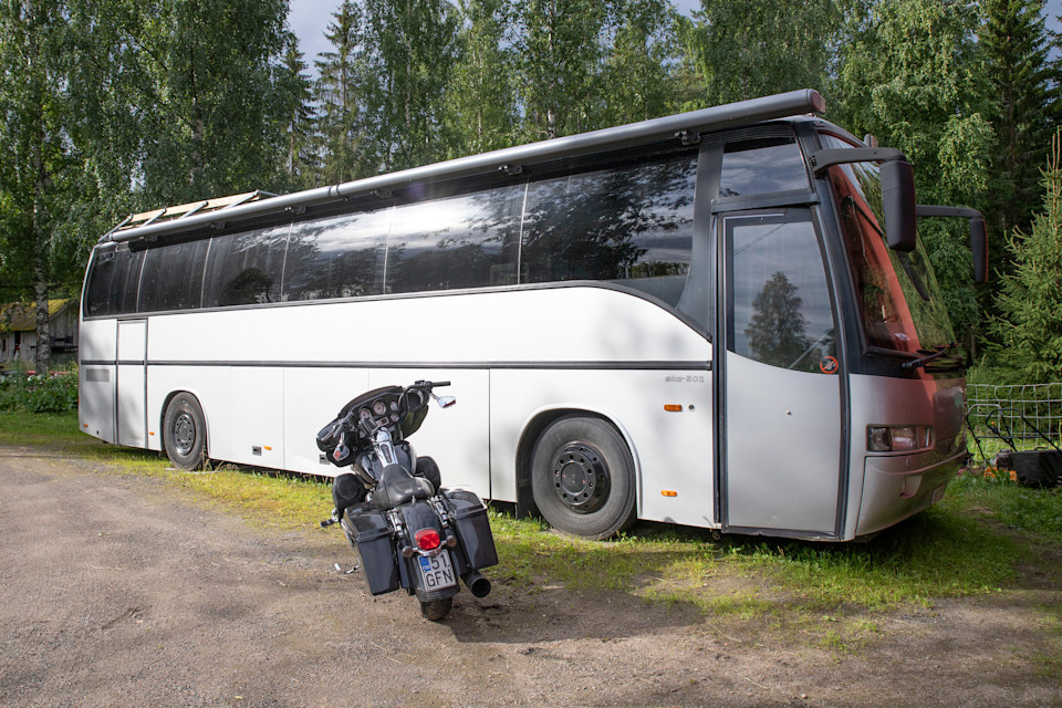 Matkailuautoksi rakentuva vanha linja-auto. Etualalla moottoripyörä.