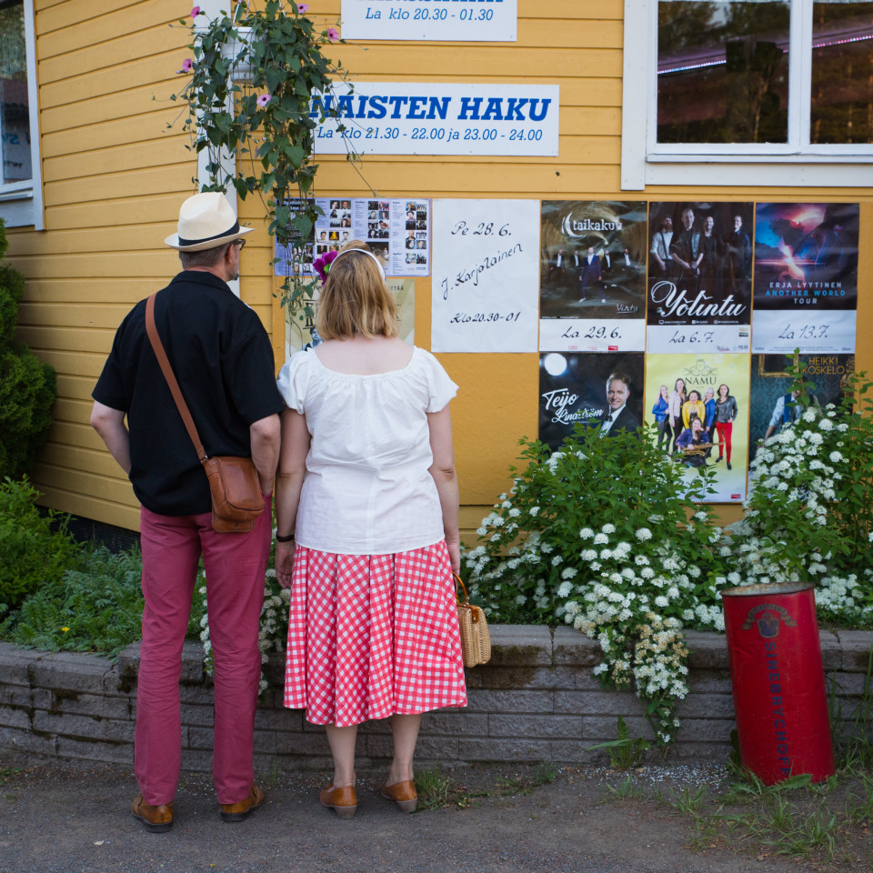 Mies ja nainen tutkivat tulevien esiintyjien mainoksia tanssilavalla.