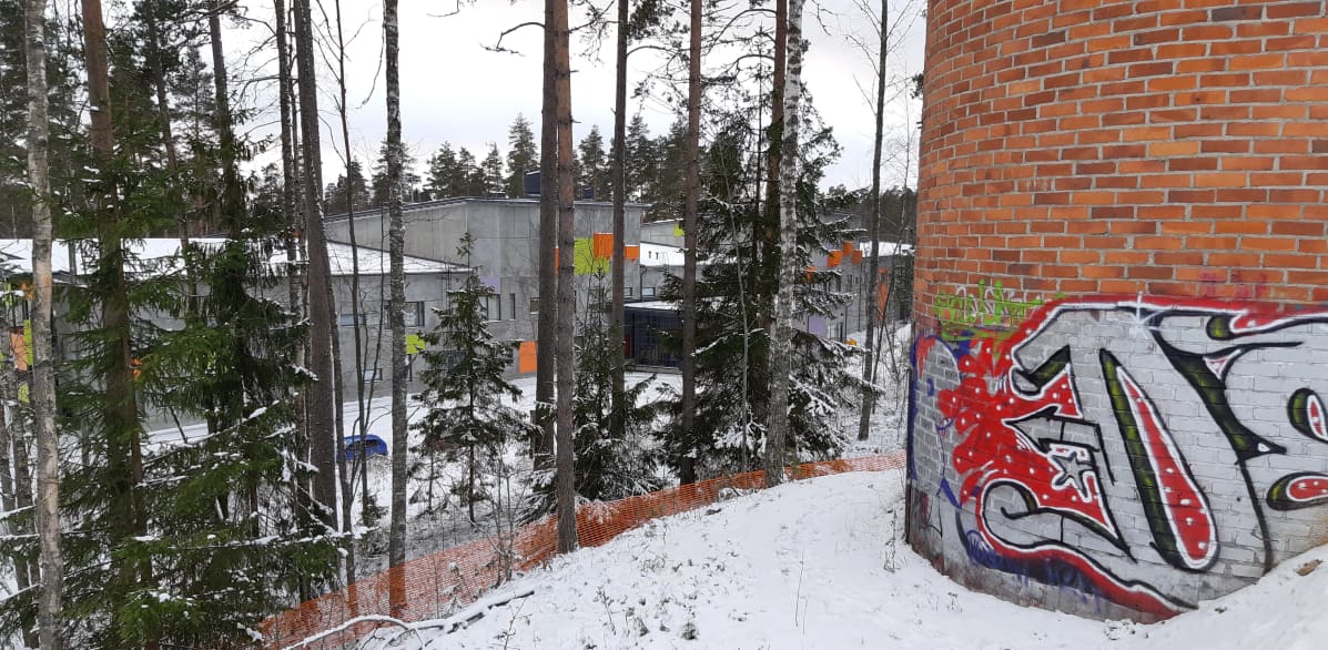 Koulurakennus mäen alla.