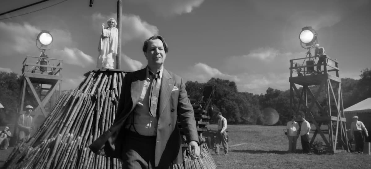 På bilden bioplanschen för filmen "Mank" som berättar historien om hur manuset till Citizen Kane blev till. Bilden är svartvit och man ser huvudpersonen spelad av Gary Oldman gå på en filminspelning, i bakgrunden syns en vitklädd kvinna.