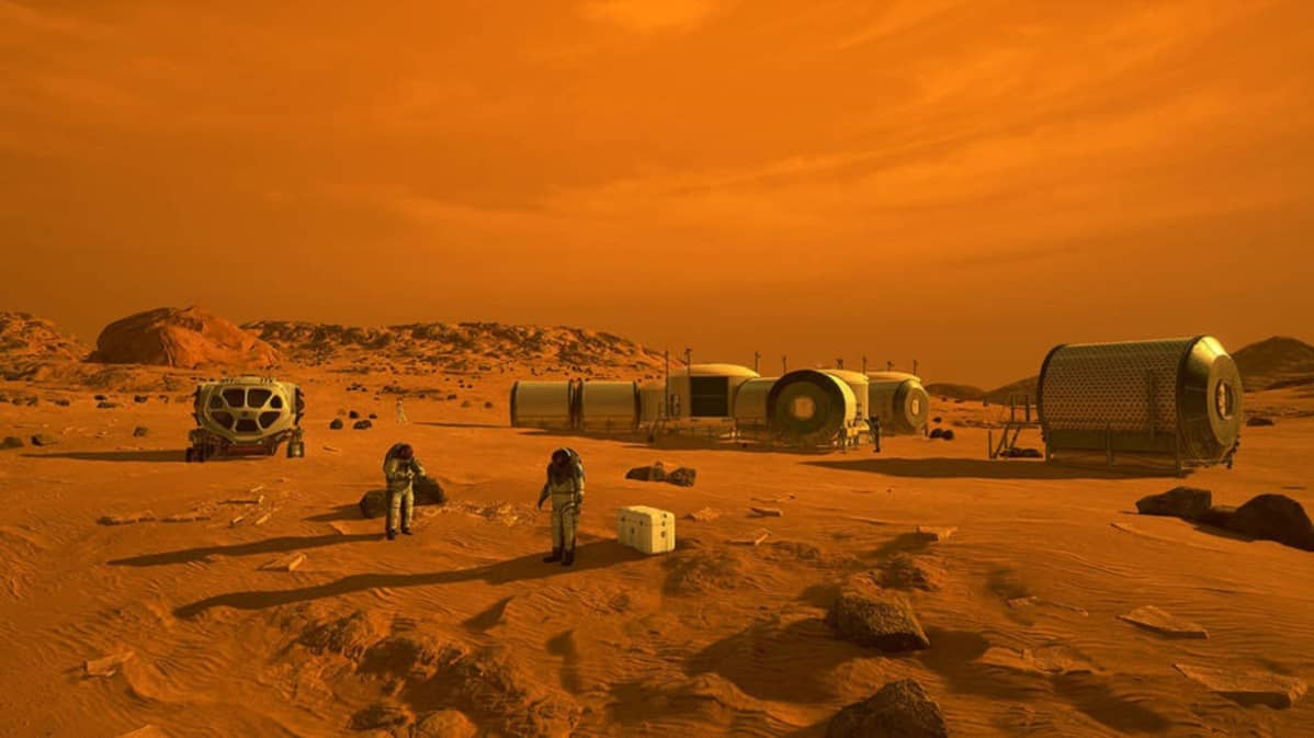 Kolme putkimaista metallirakennusta Marsin punaisella pinnalla punaisen taobaan alla. Edessä kaksi astronauttia.