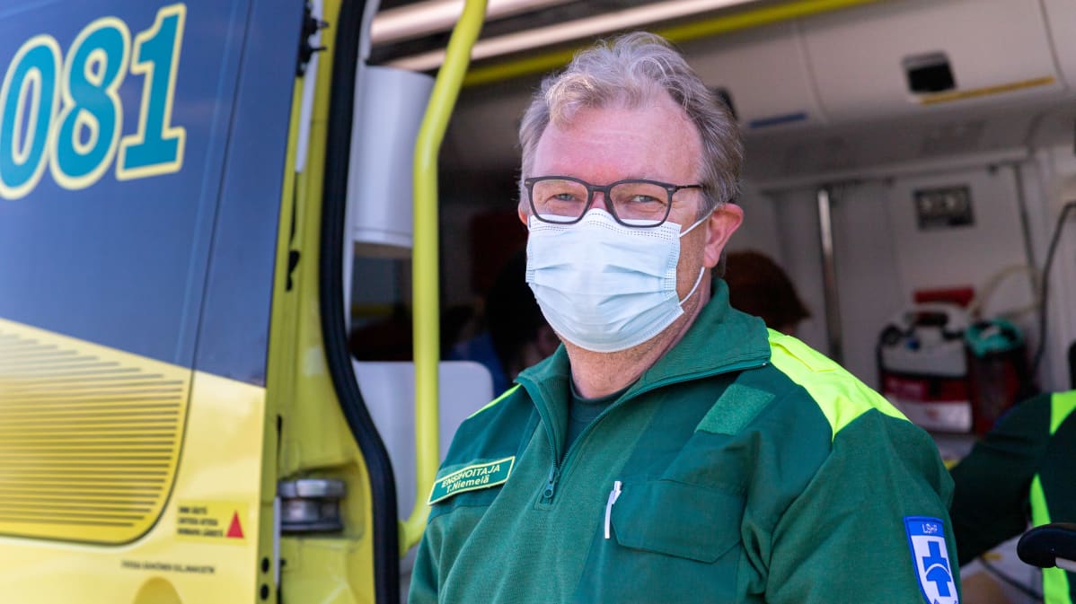 Utsjoen ensihoitaja Tapio Niemelä katsoo kameraan ambulanssin edessä.