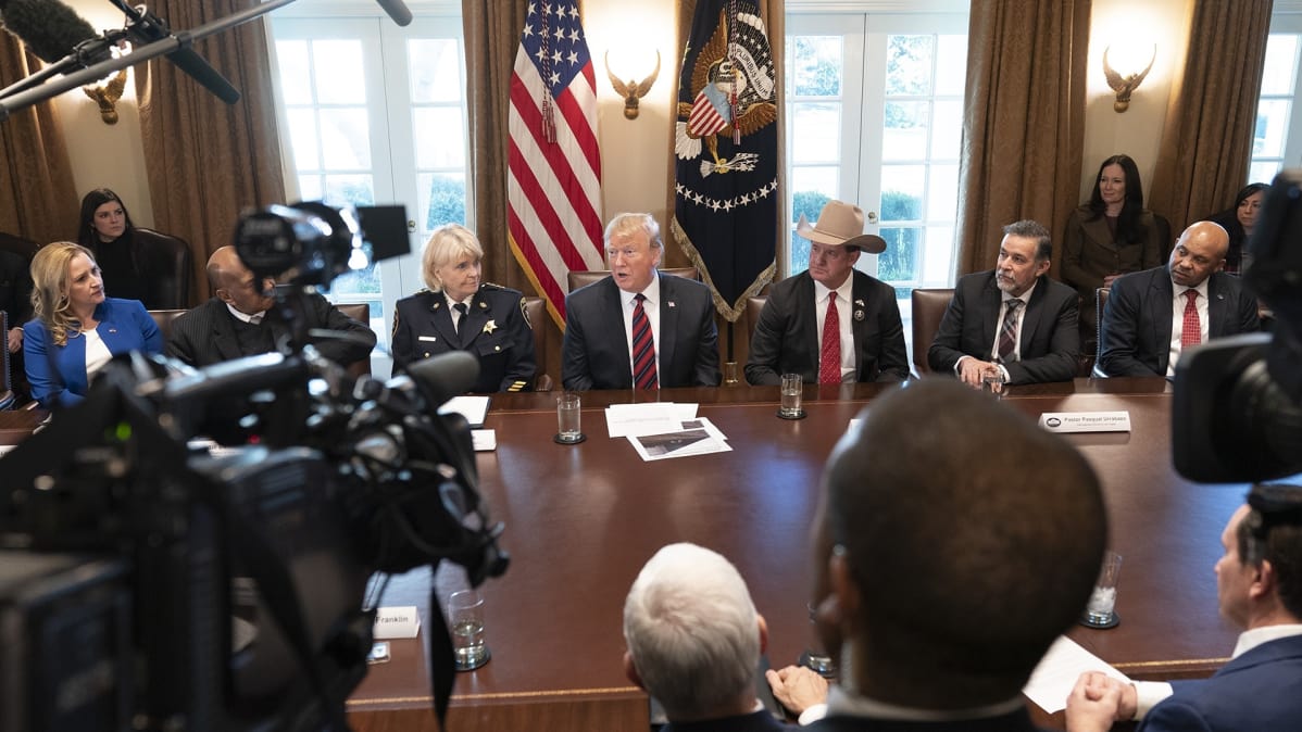 Trump puhuu joukolle pöydän äärellä.