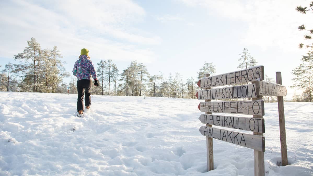 Nainen kävelee lumikengillä.