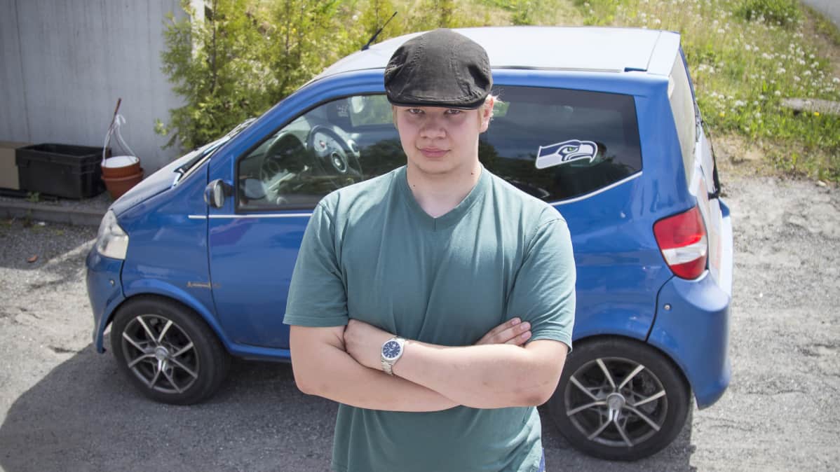 Ante Tamminen seisoo mopoauton edessä.