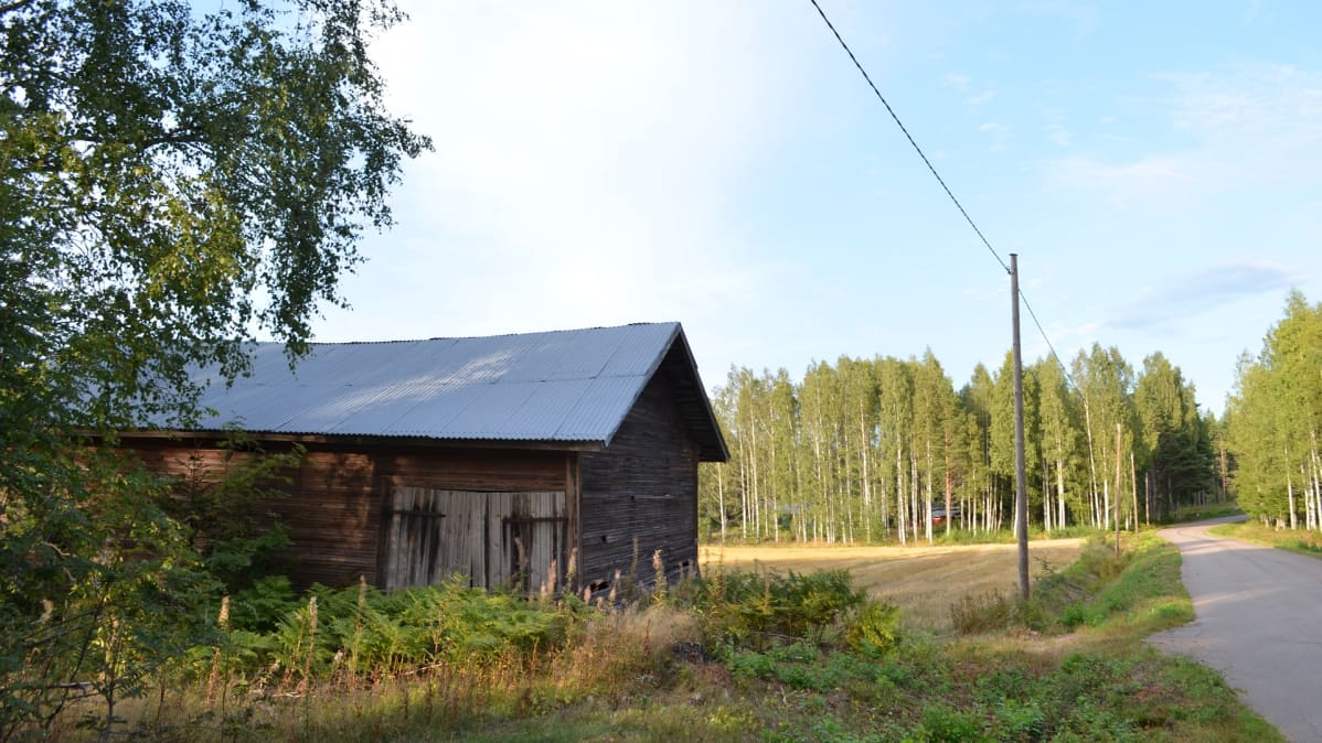Huonokuntoinen lato kapean asfaltoidun tien varressa, pellon laidalla Virolahdella.