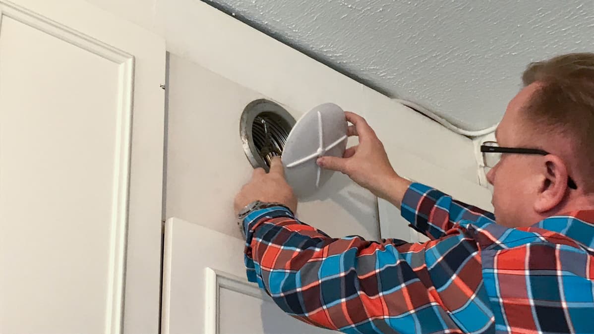 Isännöitsijä Sami Reinikka avaa asunnon poistoilmaventtiilin puhdistamista varten.