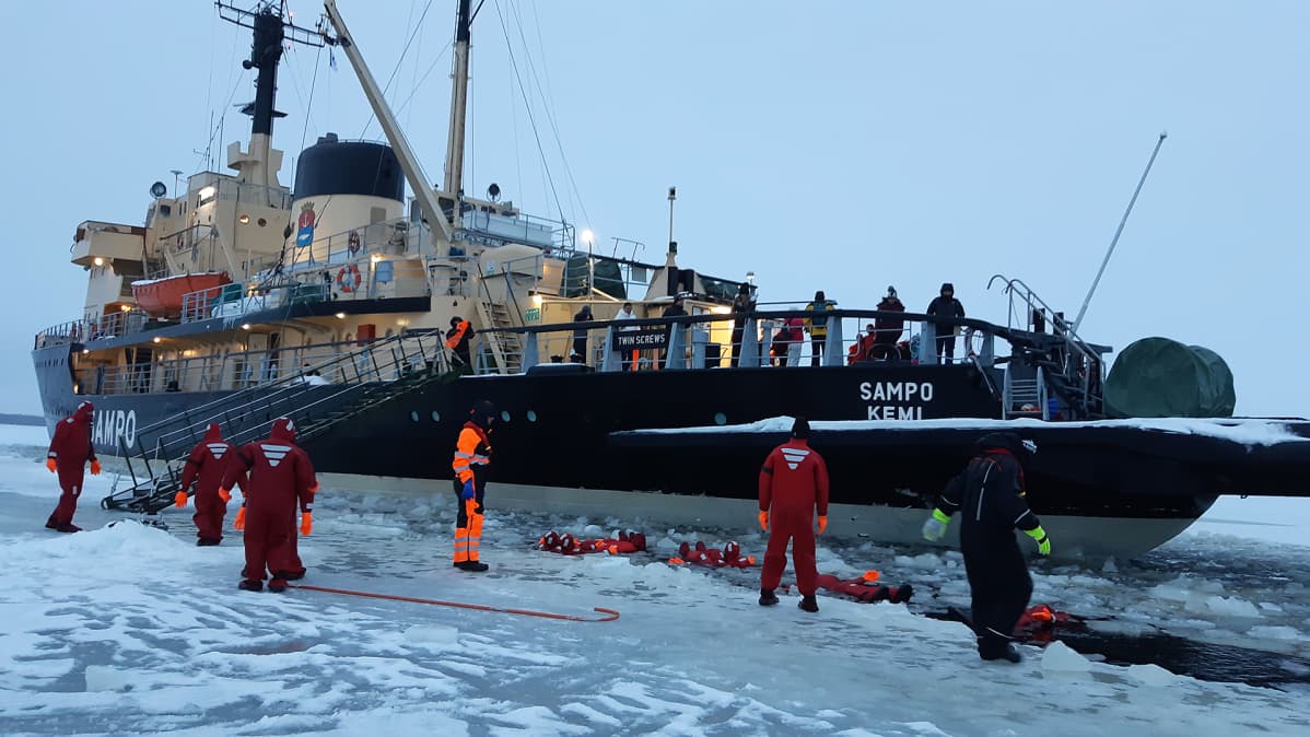 Jäänmurtaja Sampo pysähdyksissä Perämerellä kun turistit kelluvat meressä.