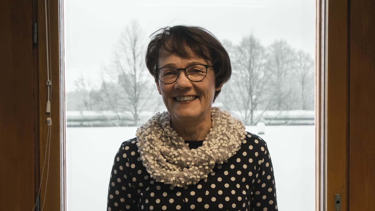 Irma Nykänen seisoo ikkunan edessä.
