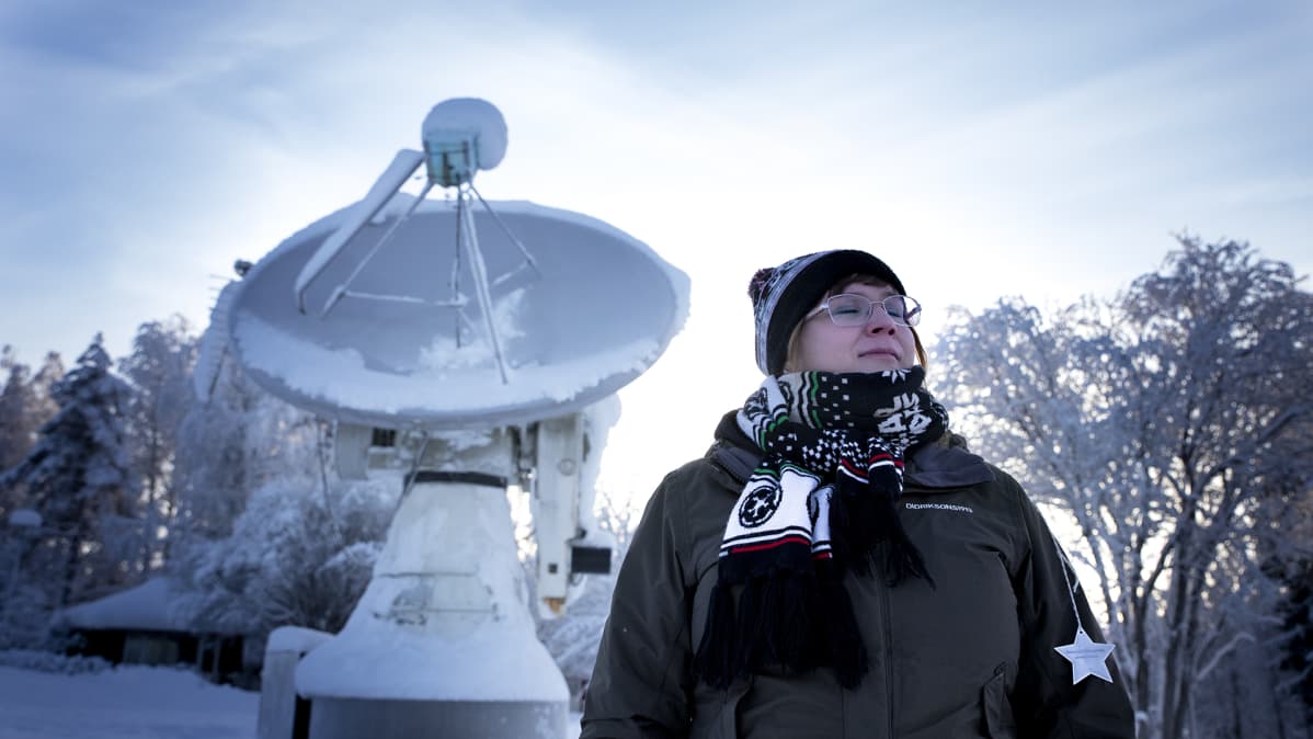 Päivikki Puolakka seisoo radioteleskoopin edessä silmät kiinni.