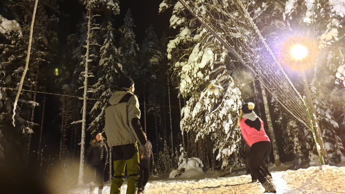 Ihmisiä pelaamassa lentopalloa talvella.