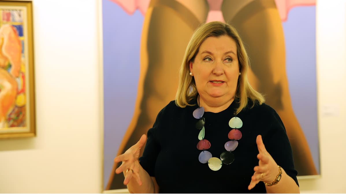 Museonjohtaja Katriina Pietilä-Juntura taustallaan Esko Tirrosen maalaus Striptease Aineen kuvataidesäätiön kokoelmista.