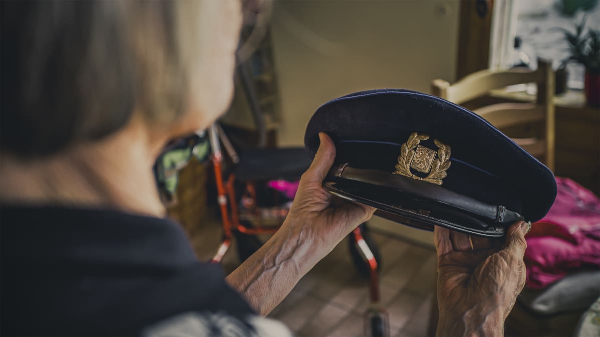 Riitta Turpeinen pitelee Pentti Turpeisen poliisilakkia.