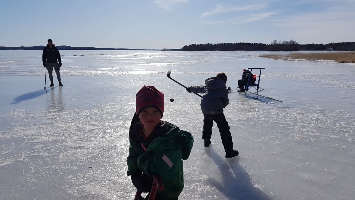 Lapset pelaavat jääkiekkoa järven jäällä