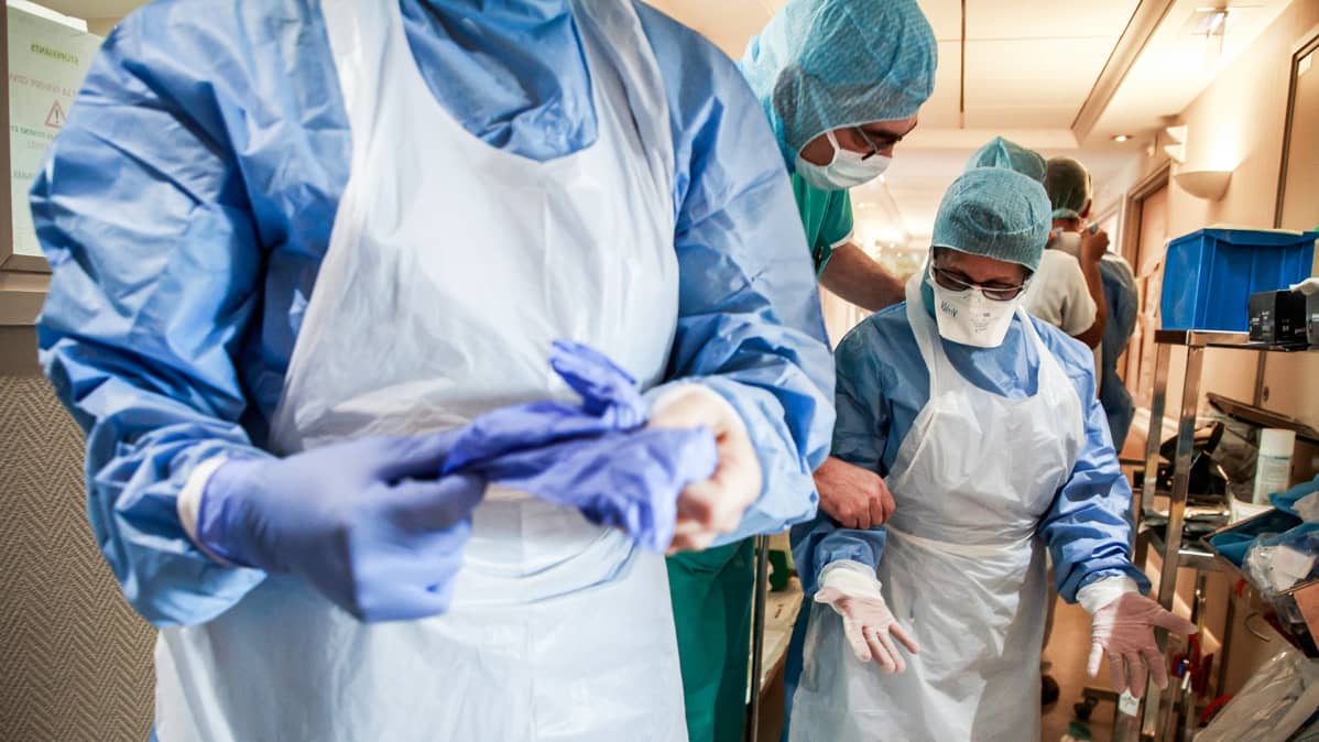 Terveydenhoitohenkilökunta pukevat suojavarusteita päälleen Ambroise Pare klinikalla Pariisissa.