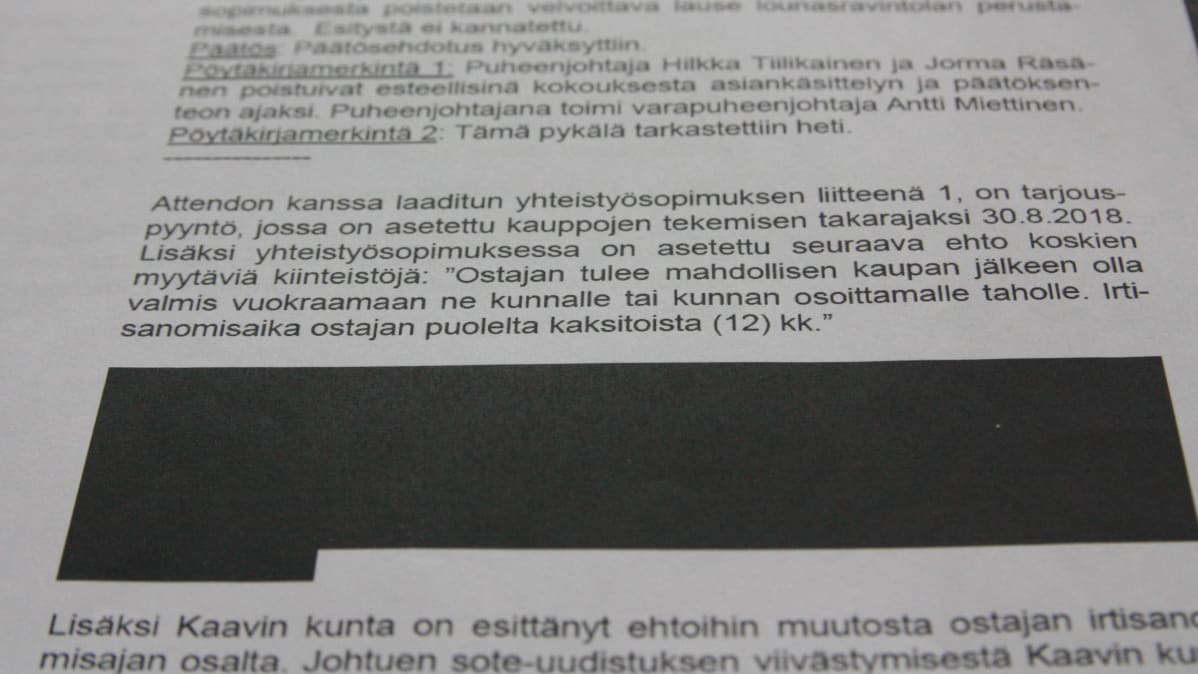 Valokuva pöytäkirjasta, jonka tekstistä osa on salattu.