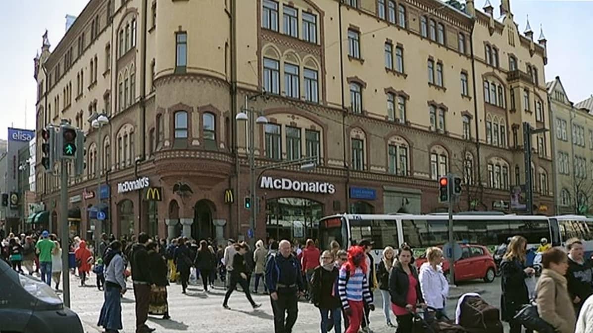 Ihmisiä kävelee suojatien yli Tampereen keskustassa Commercen talon edustalla
