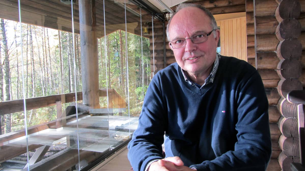 Juhani Putkisto istuu mökkinsä lasitetulla kuistilla.