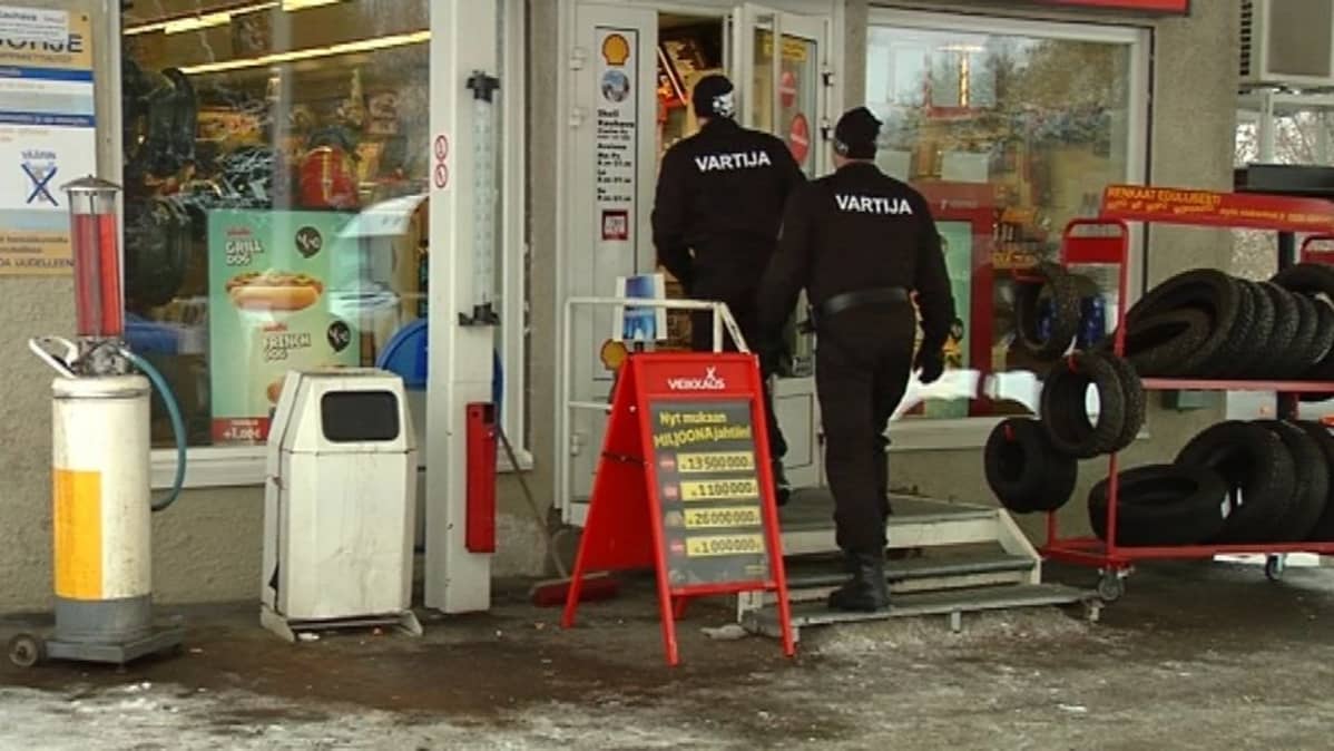kaksi vartijaa kävelee sisälle huoltoasemalla.
