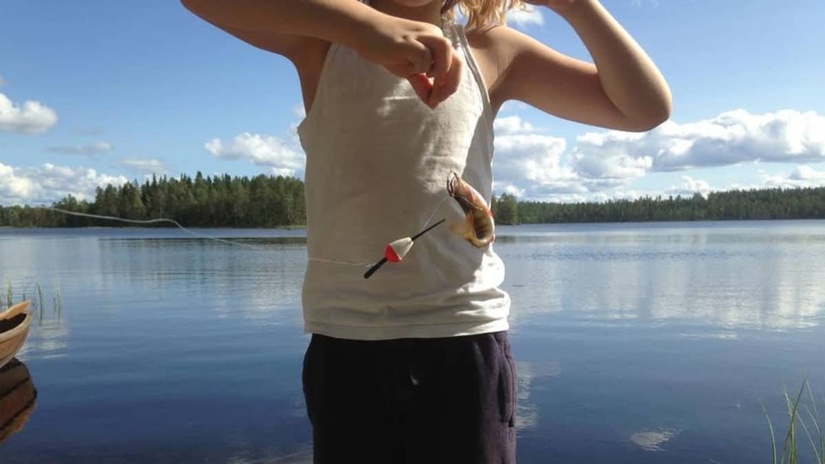 Pieni ahven pyristelee ongenkoukussa pikkupojan mato-ongessa.