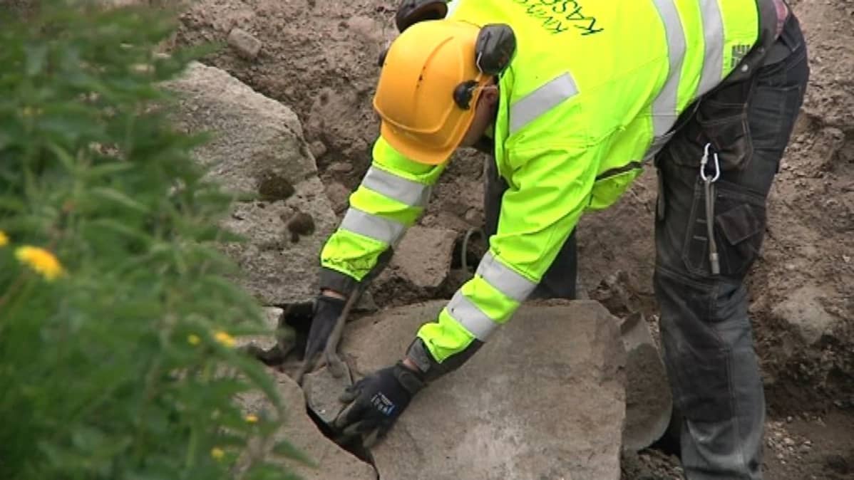 Mies asettelee kiviä vallihaudan muuriin paikalleen