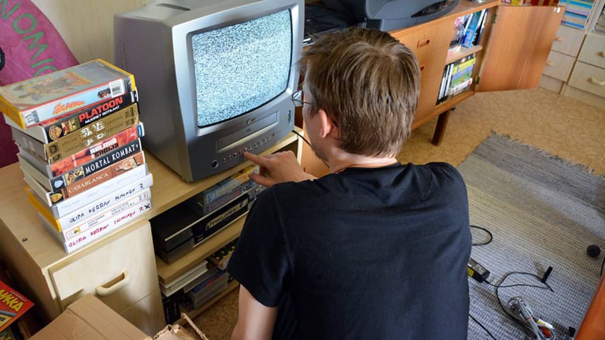 Mies virittää televisiotaan.