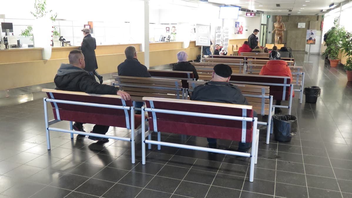 Ihmisiä istuu odottamassa Tampereen poliisiaseman lupapalveluiden aulassa.