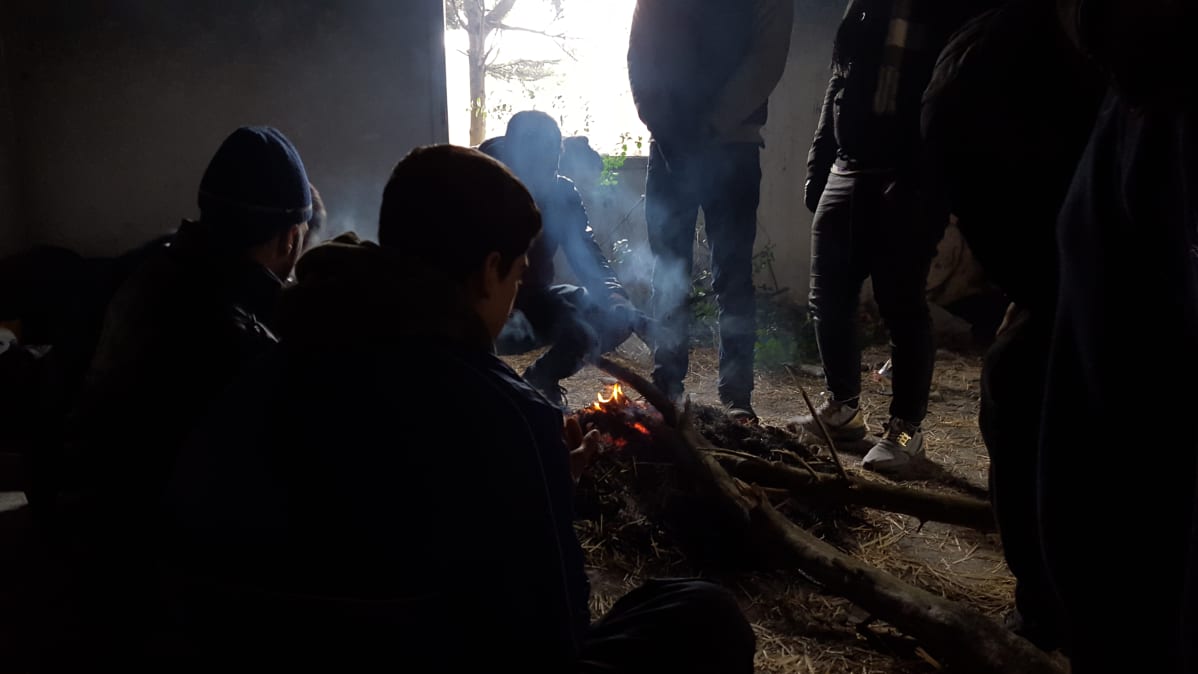 Turvapaikanhakijat lämmittelevät hyläytissä kasarmeissa Pohjois-Kreikassa.